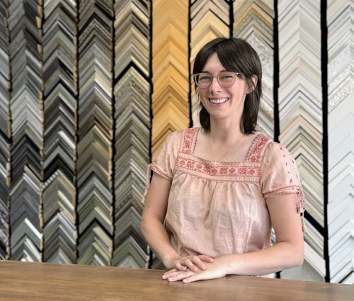 A photo of Charlotte in front of frame samples.