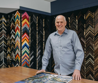 Picture of Pete in front of a wall of frame samples.